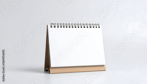 Blank spiral desk calendar with a cardboard stand, isolated on a white background for mockup or template use.