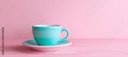 The turquoise cup and saucer on a pastel pink wooden surface, minimal lifestyle