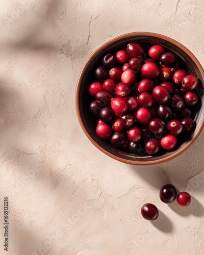 Rustic bowl of fresh cranberries on textured surface with soft light and shadows