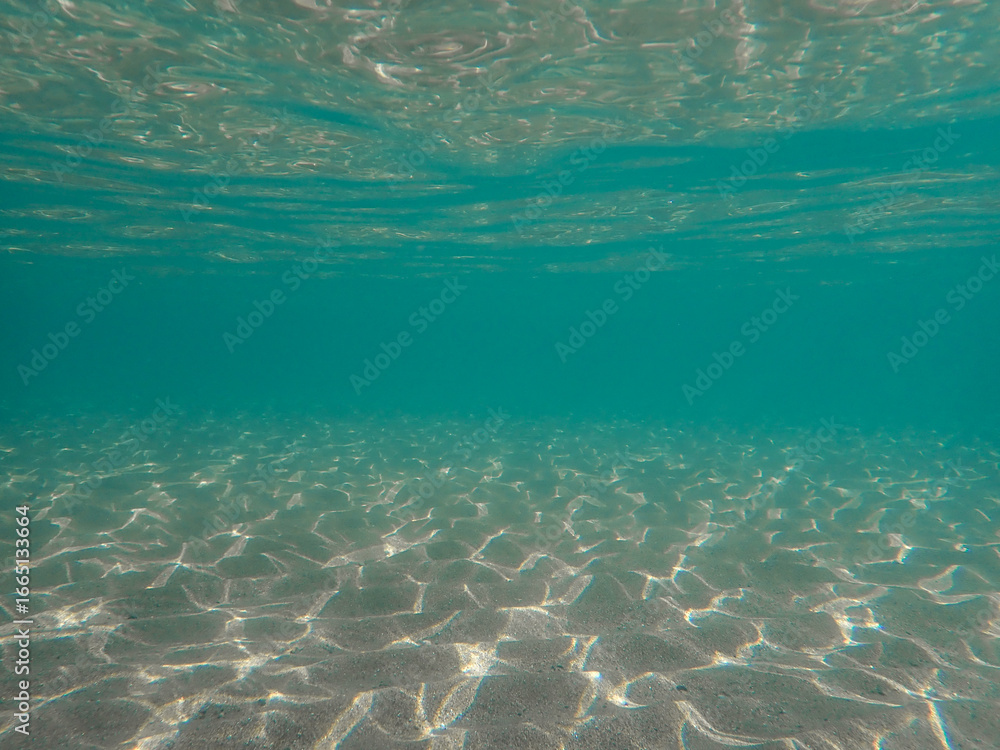 Fototapeta premium Light filtering down through blue water. Underwater sunlight in deep sea. Light viewed from blue abyss. Underwater sunlight shining deep with ripples on wave surface ocean ray, Mediterranean sea.