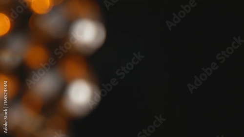 Abstract background with a boke effect with orange flashes. Bright highlights of unfocused blurred light. Optical glow of confetti flicker in the dark