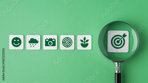 Magnifying glass focuses on target icon amidst row of diverse lifestyle and goal oriented symbols