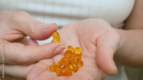 Omega 3 in the hands of a woman in close-up. Medicines, tablets and gelatin capsules with omega-3 oil. The concept of healthcare. Pharmaceutical preparations