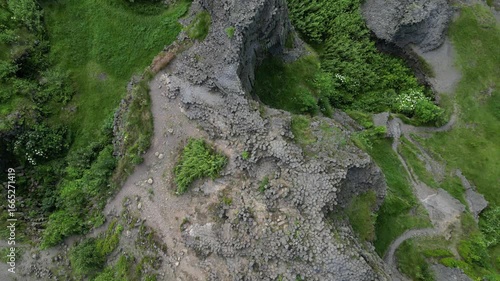 Aerial drone footage of Panská skála in the Czech Republic, a unique volcanic basalt rock formation resembling organ pipes. Scenic view showcasing dramatic geology, natural monument.