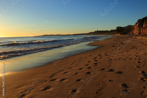 The sea beach at sunset. The yellow rays of the sun turn the waves golden