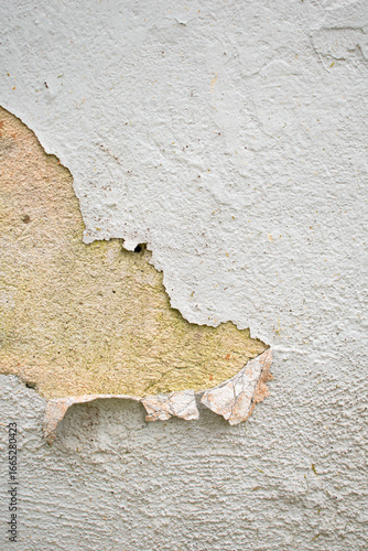 Imagen vertical de una pared desgastada con la pintura blanca cayendose