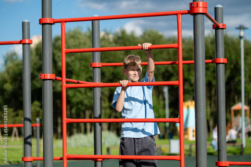 Obraz premium Teen boy climbing ladder on playground with sports equipment