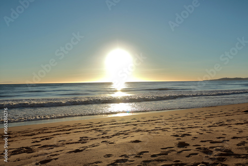 A very bright solar disk sets over the horizon