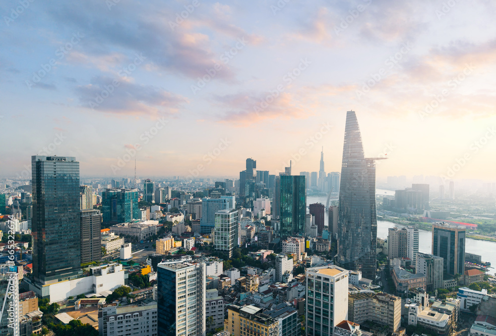 Fototapeta premium Aerial view of Ho Chi Minh City skyline and skyscrapers on Saigon river. Financial business center at downtown sunset time.