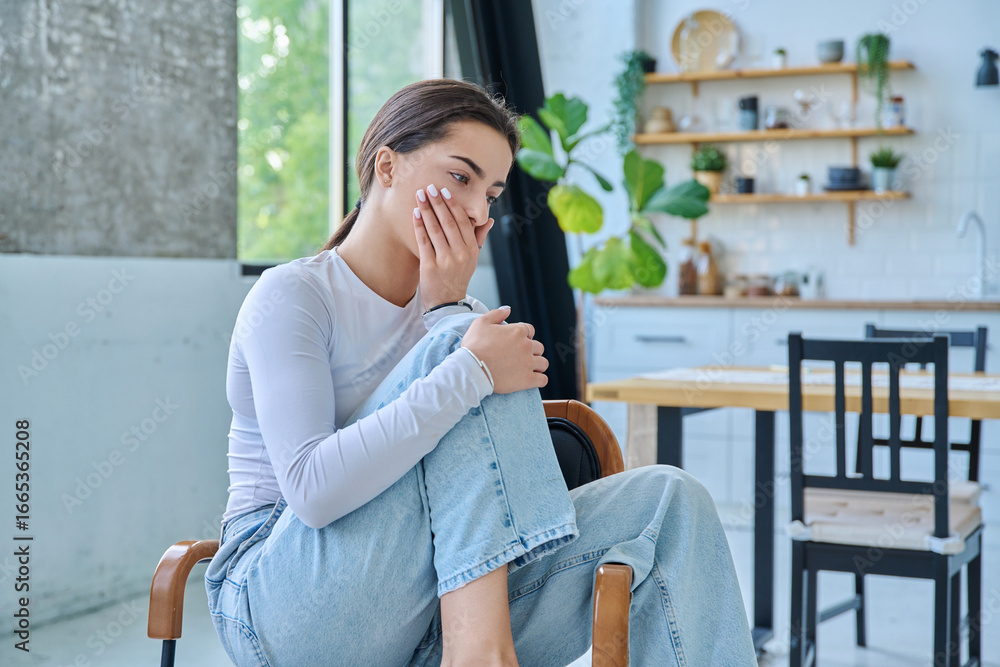 Fototapeta premium Sad upset teenager girl sitting at home in living room