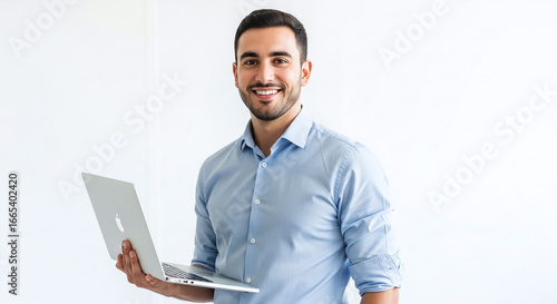 Smiling man in blue shirt holding a laptop computer against a plain white background in a studio shot