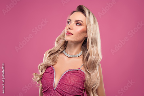 Charming woman in glamorous dress with luxurious jewelry on pink background, showcasing stylish and beautiful fashion