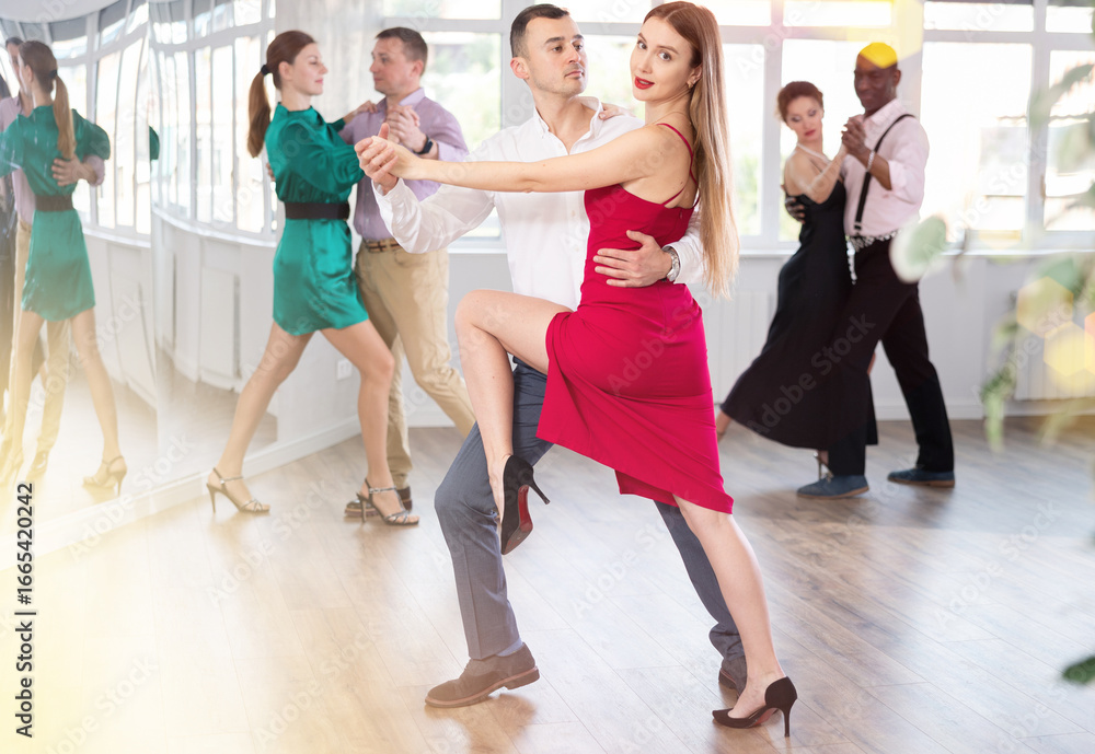 Naklejka premium Woman paired with man practices movements of Latin tango dance and trains to perform movements during lesson in choreography studio.