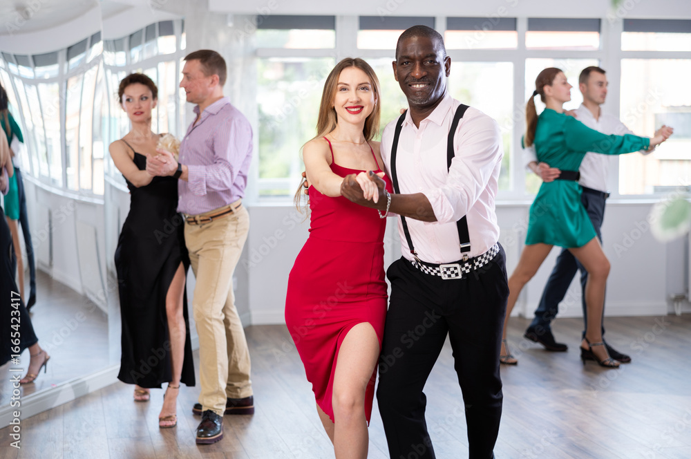 Naklejka premium Active young woman training waltz in pair with man in dance-hall during dancing classes