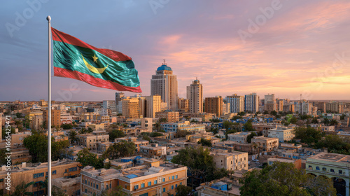 Mauritania flag waving against a vibrant sunset in the cityscape on Independence Day