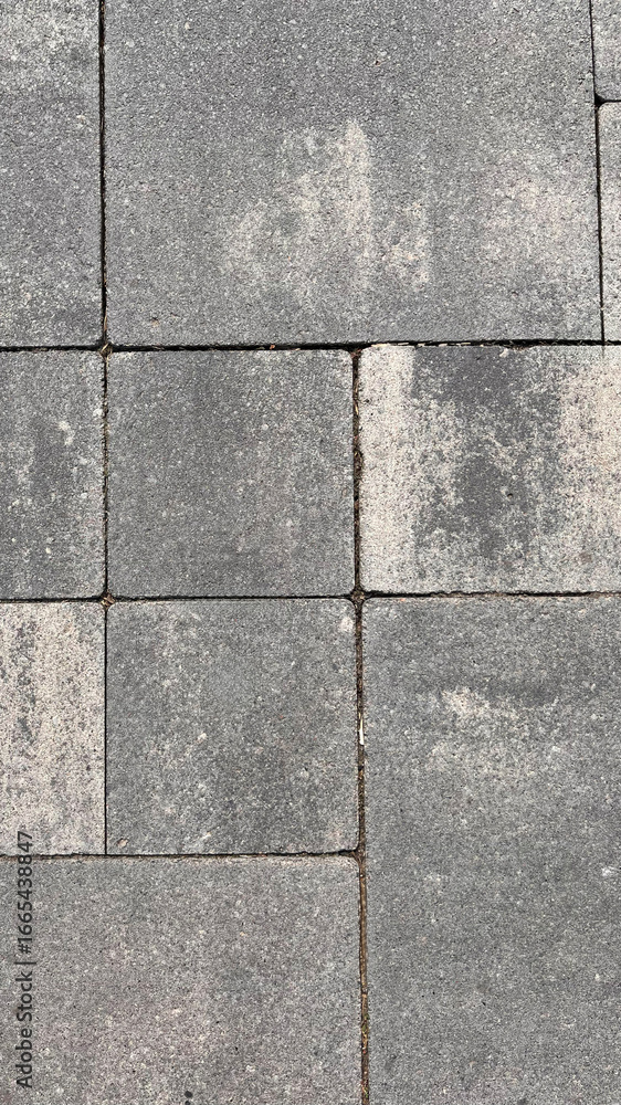 Obraz premium Textured pavement with visible wear captured during daytime in an urban environment