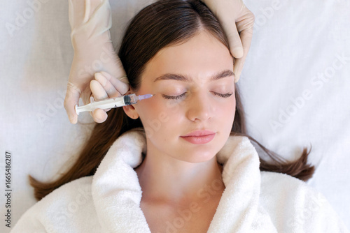 Schilderij op canvas Cosmetologist making botox injection for eyes area to young woman, lady getting