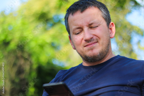 Man using smartphone in a green outdoor setting