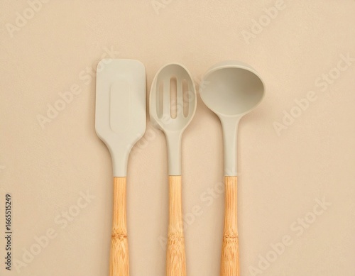 Three kitchen utensils, a spatula, slotted spoon, and ladle, arranged on a neutral background.