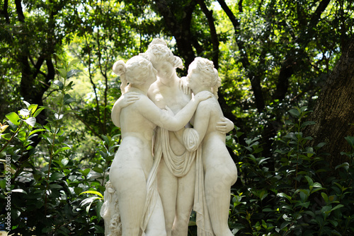 Photograph of a sculpture of divine women muses made of white marble with a natural organic background.