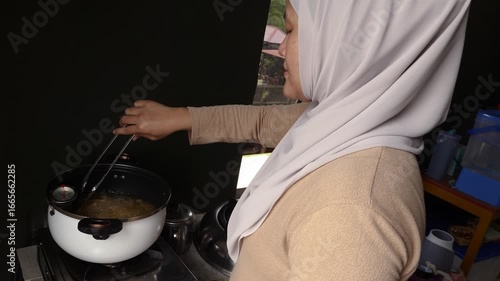 Asian muslim woman deep frying chicken in hot oil