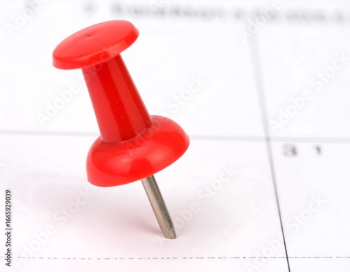 Red pushpin on a calendar page