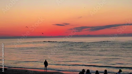 Time lapse footage of sunrise on the Black Sea beach with silhouettes of people on the shore