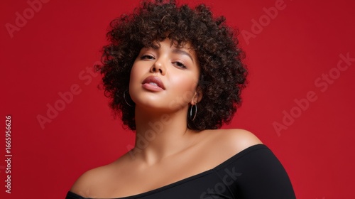 Young plus-size woman with afro hairstyle in minimalist black outfit against saturated red backdrop, bold and empowering 