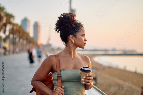 Photography Tourist enjoying a takeaway coffee on Barceloneta beach in Barcelona at sunrise,