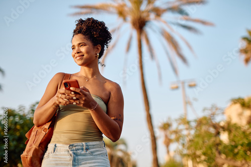 Canvas Print Young woman using mobile phone in Los Angeles with palm trees in the background