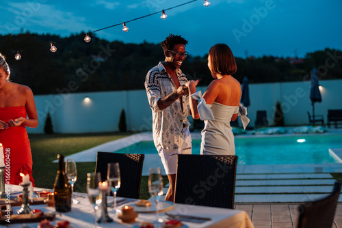 Fototapeta Friends dancing at a pool party enjoying summer holidays