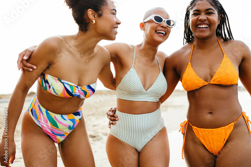 Playful friends in swimwear with arms around at beach