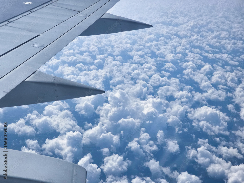 Obraz premium Beautiful cumulus clouds from the airplane window. Picturesque view from the airplane window at dawn.