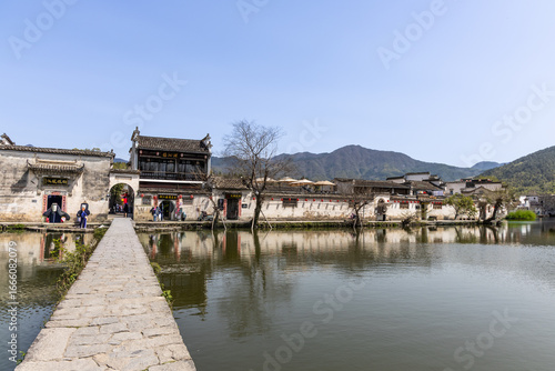 Crossing the Hongcun ancient village arch bridge within the serene South lake in Anhui province, China.