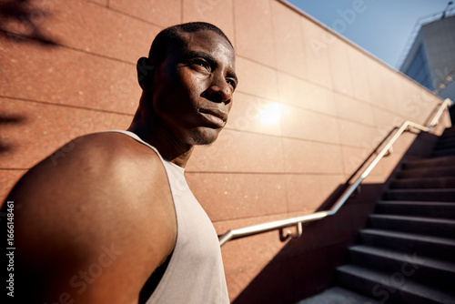 Canvas Print Confident athlete standing outdoors against wall in bright sunlight