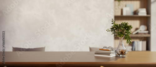 Glasses and pencil atop books aside vase on wooden table in a room with loft wall and build in shelf
