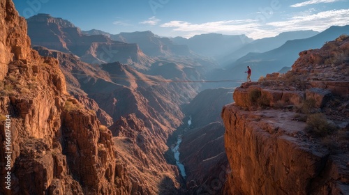 A person stands on a cliff edge overlooking a vast canyon landscape at sunset