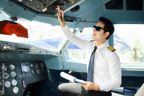 Wall Mural Professional airline pilot in uniform inspecting cockpit control panels during safety checks, ideal for aviation, travel, and airline safety themes