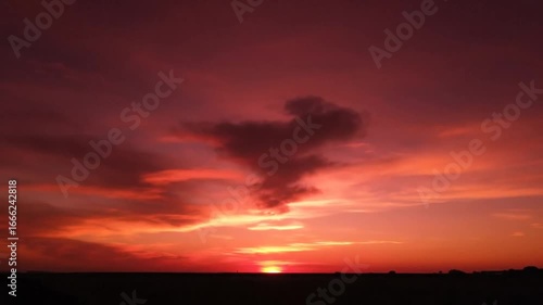 Dramatic sunset with unique cloud formation resembling a bird in silhouette against a fiery sky.