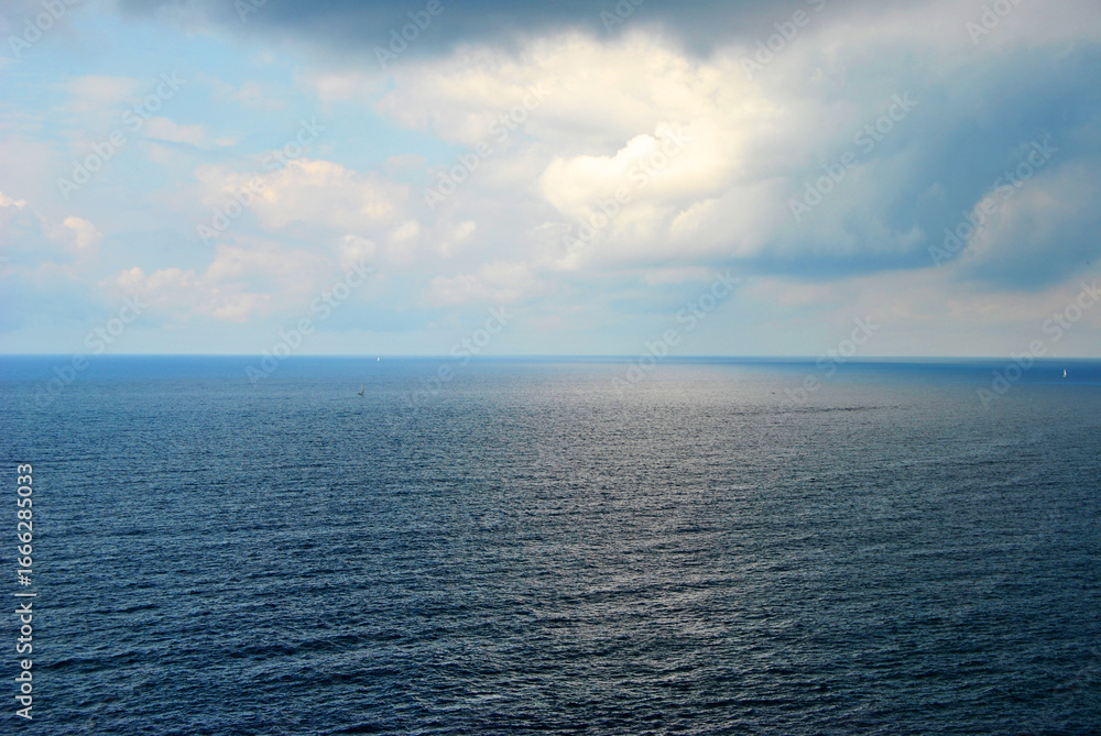 Fototapeta premium Calm sea under cloudy sky with sun rays