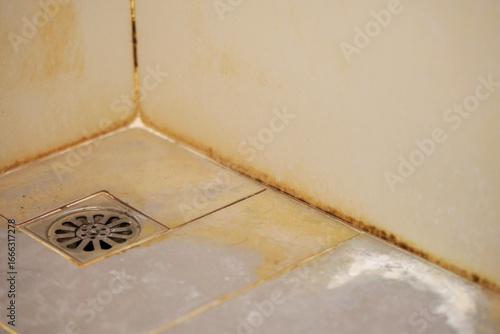 bathroom with a toilet. dirty joints between the tiles, toxic black mold in the corner. Clogged and dirty sewer pipes floor drain.