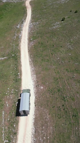 Aerial drone view of a TAM truck driving along rough mountain dirt roads, representing adventure travel, rural transport and off-road experience in nature.
