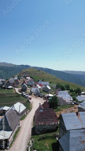 Aerial drone footage flying over traditional stone houses in Lukomir, the highest village in Bosnia and Herzegovina, located on mountain Bjelašnica. Scenic rural settlement with panoramic mountain lan