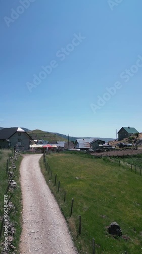 Aerial drone footage flying over traditional stone houses in Lukomir, the highest village in Bosnia and Herzegovina, located on mountain Bjelašnica. Scenic rural settlement with panoramic mountain lan