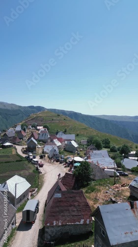 Aerial drone footage flying over traditional stone houses in Lukomir, the highest village in Bosnia and Herzegovina, located on mountain Bjelašnica. Scenic rural settlement with panoramic mountain lan