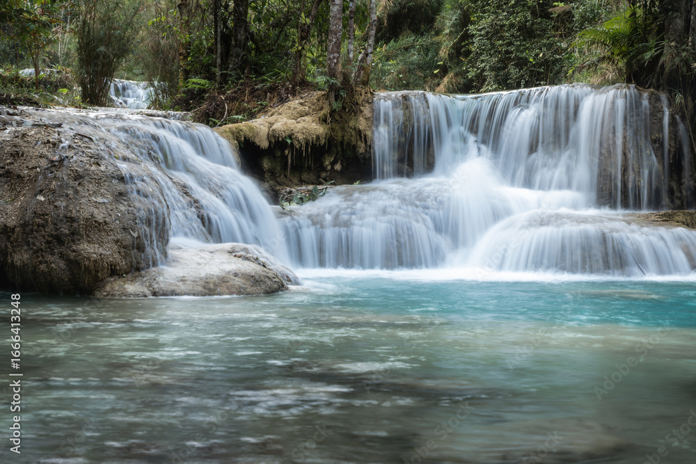 Obraz premium Kuang Si Waterfall flowing into a clear blue forest river in Luang Prabang, Laos
