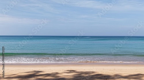 A scenic view of the sandy beach and clear blue ocean under a bright sky