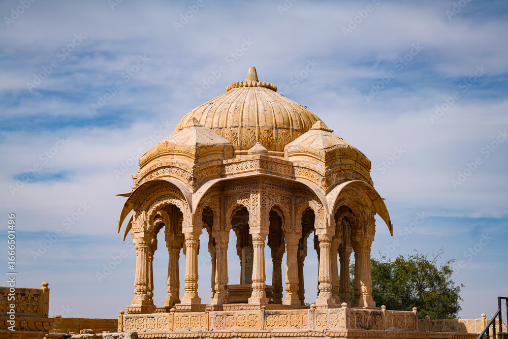 Fototapeta premium Sandstone cenotaph with intricate Rajput architecture stands as a heritage landmark, showcasing cultural history and timeless craftsmanship in Jaisalmer, Rajasthan.
