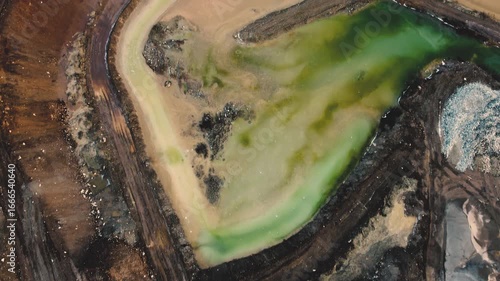 Drone fly over a gravel quarry with green and yellow water ponds - Concept of environmental impact