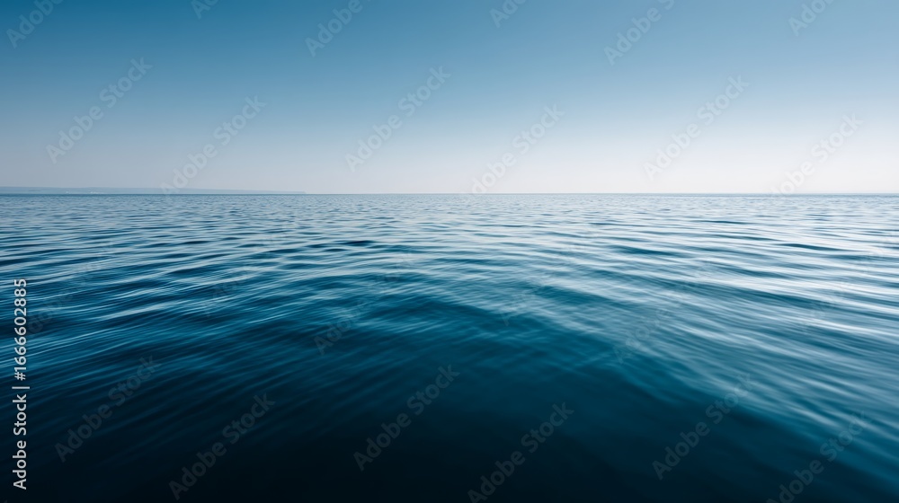 Fototapeta premium Calm blue water surface with gentle ripples under clear sky, peaceful nature scene with copy space on left, wideangle view